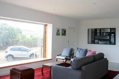 a living room with a couch and a window at Swallows Perch Beach Getaway - Solar Backup in Bettyʼs Bay