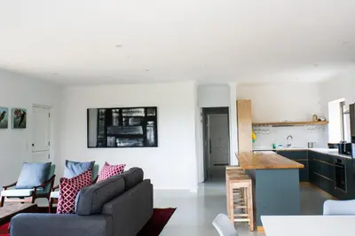 a living room with a couch and a kitchen at Swallows Perch Beach Getaway - Solar Backup in Bettyʼs Bay