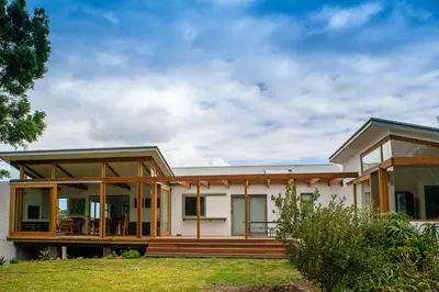 a home with a large porch and a house at Swallows Perch Beach Getaway - Solar Backup in Bettyʼs Bay