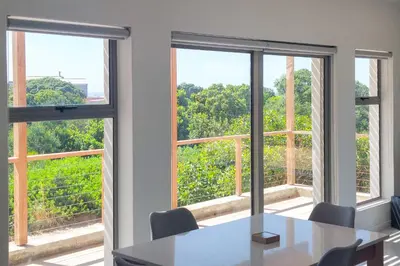 a table and chairs in a room with windows at Swallows Perch Beach Getaway - Solar Backup in Bettyʼs Bay