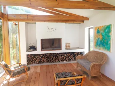 a living room with a fireplace and a chair at Swallows Perch Beach Getaway - Solar Backup in Bettyʼs Bay