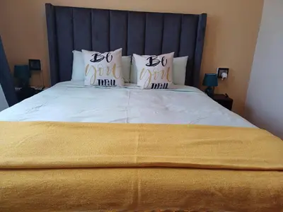 a bed with a blue headboard and pillows on it at Oakway Guest Suite 2 Beds 1Bath Aircon Kitchen Private in Kuilsrivier