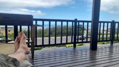 a persons feet on a bench on a balcony at La Mer in Bettyʼs Bay