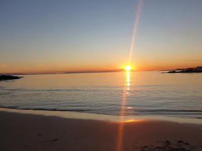 a sunset on the beach with the sun setting at 'Goldwater on Beach' - 3 Bedroom Beachfront with Balcony & BBQ - Sleeps 6 in Gordonʼs Bay