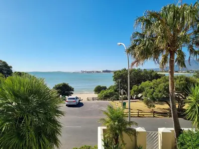a car parked in a parking lot next to the beach at 'Goldwater on Beach' - 3 Bedroom Beachfront with Balcony & BBQ - Sleeps 6 in Gordonʼs Bay