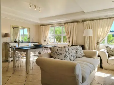 a living room with a couch and a table at 'Goldwater on Beach' - 3 Bedroom Beachfront with Balcony & BBQ - Sleeps 6 in Gordonʼs Bay