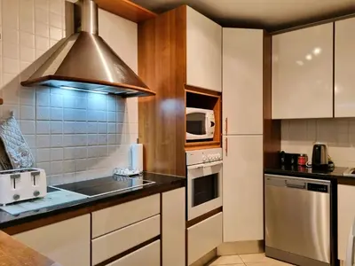 a kitchen with a sink and a stove at 'Goldwater on Beach' - 3 Bedroom Beachfront with Balcony & BBQ - Sleeps 6 in Gordonʼs Bay