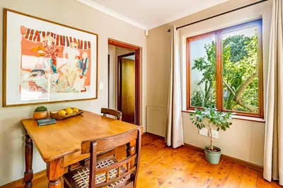 a dining room with a wooden table and a window at 5 on Paul Kruger in Somerset West