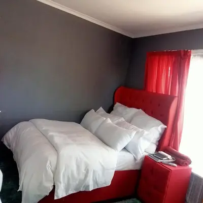 a bed with a red headboard and white sheets and pillows at Fairbridge Queens and Kings Guest House in Cape Town