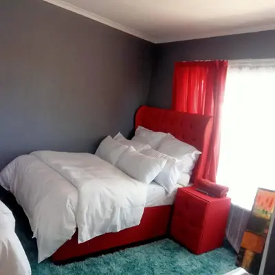 a red bed with white sheets and pillows in a bedroom at Fairbridge Queens and Kings Guest House in Cape Town