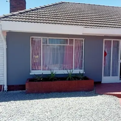 a blue house with plants in front of a window at Fairbridge Queens and Kings Guest House in Cape Town