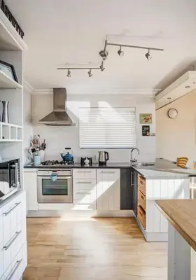 a kitchen with white cabinets and a wooden floor at Onrus Beach House in Hermanus