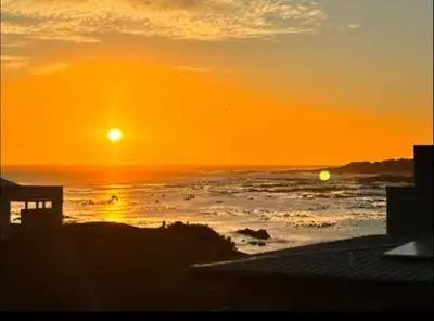 a sunset over the ocean with the sun setting at Onrus Beach House in Hermanus