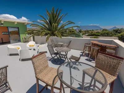 a patio with chairs and tables on a balcony at Cape Town 4U Guesthouse in Cape Town
