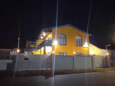 a yellow house behind a fence at night at Neo & Ruks Guest Houses parow 4 in Avondale