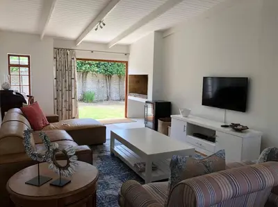 a living room with couches and a flat screen tv at Onrus Home with a Sea View in Hermanus