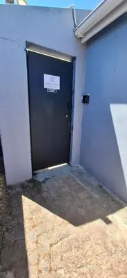 a garage with a black door with a sign on it at Grey Vine Cottage - Guest Room in Cape Town