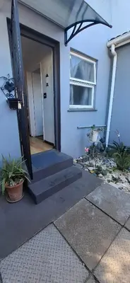 a blue house with a door and a window at Grey Vine Cottage - Guest Room in Cape Town