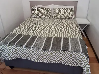 a bed with a black and white comforter and pillows at Grey Vine Cottage - Guest Room in Cape Town