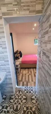 a bedroom with a pink bed and a bathroom at Neo & Ruks Guest Houses Boston Belleville 6 in Bellville