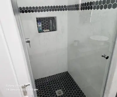 a bathroom with a shower with a black and white tile floor at Somerset west Stay 1 in Somerset West