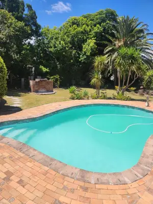 a swimming pool with blue water in a yard with trees at Somerset west Stay 1 in Somerset West