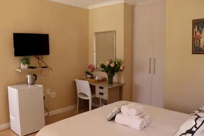 a bedroom with a bed with a desk and a mirror at Tygerviews on Uys in Tygerberg Hills