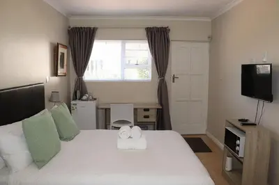 a bedroom with a white bed and a television at Tygerviews on Uys in Tygerberg Hills