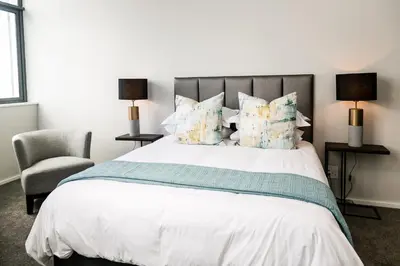 a bedroom with a large bed and a chair at Luxury Three Bedroom Axis- Ocean and Mountain Views in Cape Town