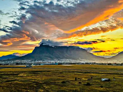 a sunset over a field with a mountain in the background at Luxury Three Bedroom Axis- Ocean and Mountain Views in Cape Town