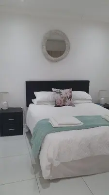 a white bedroom with a large bed with a mirror at Comfey Stay in Somerset West
