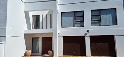 a white building with two garage doors and windows at 33 on Vermont in Hermanus
