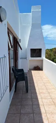 a black bench sitting on a balcony with a fireplace at 33 on Vermont in Hermanus