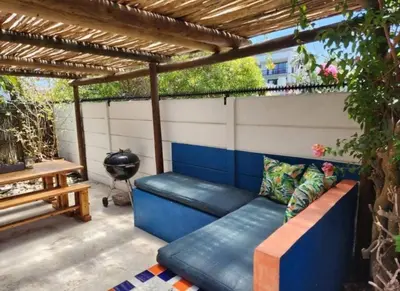 a patio with a blue couch under a pergola at Crinum House and cottages in Bloubergstrand in Cape Town