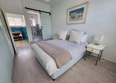 a bedroom with a bed and a table with a lamp at Crinum House and cottages in Bloubergstrand in Cape Town