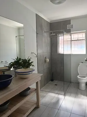 a bathroom with a toilet and a glass shower at Crinum House and cottages in Bloubergstrand in Cape Town