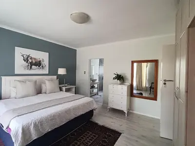 a bedroom with a large bed and a mirror at Crinum House and cottages in Bloubergstrand in Cape Town