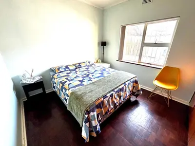 a bedroom with a bed and a window and a chair at One Bedroom House in Goodwood