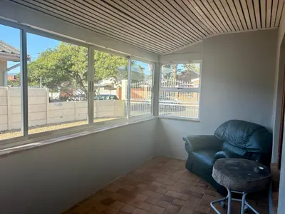 a room with a chair and a table and windows at One Bedroom House in Goodwood