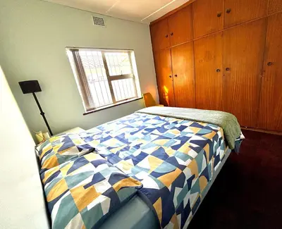 a bedroom with a bed with a blue and yellow quilt at One Bedroom House in Goodwood