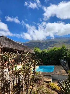 a resort with a swimming pool and mountains in the background at Serendipity Self-Catering Cottage in Greyton