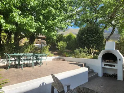 a patio with a table and chairs and a fireplace at Serendipity Self-Catering Cottage in Greyton