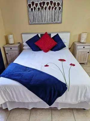 a bed with blue and red pillows on it at 22 on Shiraz in Hoheizen