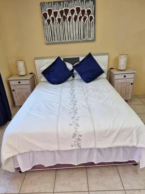 a bedroom with a white bed with blue pillows at 22 on Shiraz in Hoheizen
