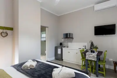 a bedroom with a bed and a kitchen with a table at Twelve on Arum in Somerset West