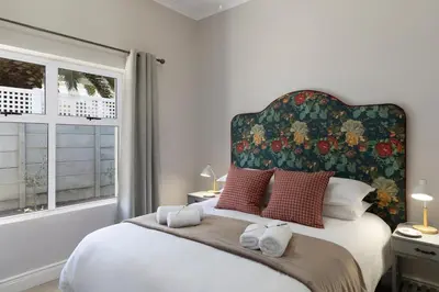 a bedroom with a large bed with a floral headboard at Twelve on Arum in Somerset West