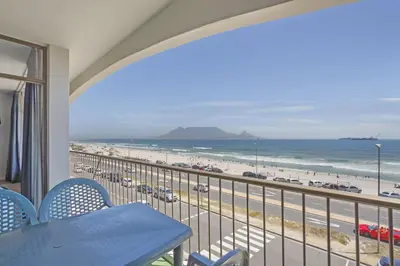 a balcony with a table and chairs and a view of the beach at Witsand 303 in Cape Town