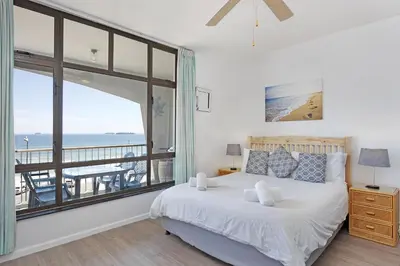 a bedroom with a bed and a view of the ocean at Witsand 303 in Cape Town