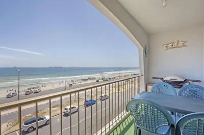 a balcony with a table and chairs and a view of the beach at Witsand 303 in Cape Town