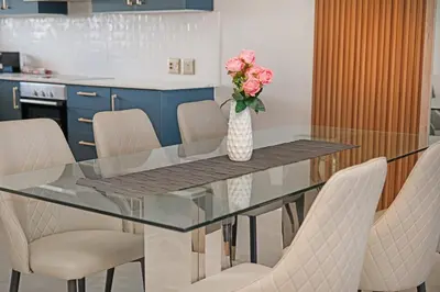 a glass dining room table with chairs and a vase of flowers at Ultra Luxury 3 Bed Knightsbridge Penthouse in Cape Town
